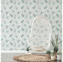 Dekoratives Zimmer mit floraler Tapete, Rattansessel und rundem Teppich.