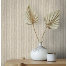 Nahaufnahme einer Wand mit Strickmuster-Tapete, dekoriert mit einer Vase und getrockneten Palmenblättern auf einem Holztisch.