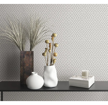 Dekoratives Interieur mit gemusterter Tapete, Vasen, Dekoration und Kerze auf einer schwarzen Oberfläche.