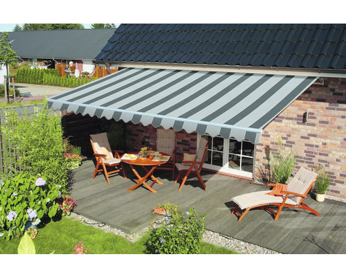 Terrasse mit Markise, Gartenmöbeln und Pflanzen vor einem Wohnhaus