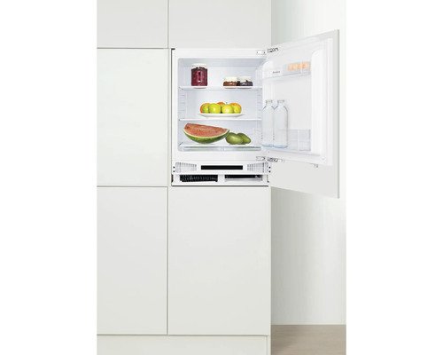 Geöffneter Einbaukühlschrank gefüllt mit Lebensmitteln in einer weißen Küchenzeile.