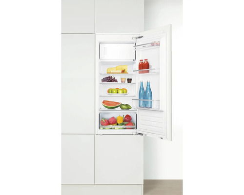 Integrierter Kühlschrank mit geöffneter Tür, gefüllt mit Lebensmitteln wie Käse, Obst und Gemüse.