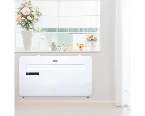 Szene mit einem weißen Klimagerät an einer Wand in einem Raum mit Fenster und Dekorationen.