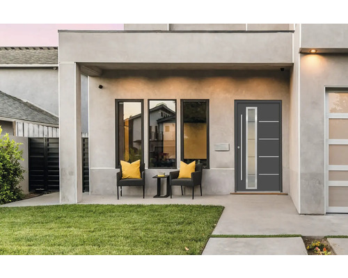 Hausfassade mit Haustür, Fenstern und Sitzbereich auf der Terrasse