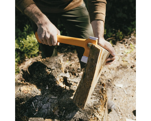 Eine Person spaltet mit einer Spaltaxt Holz auf einem Hackklotz.