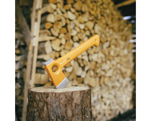 Fiskars Spaltaxt auf einem Holzscheit vor einem Holzstapel