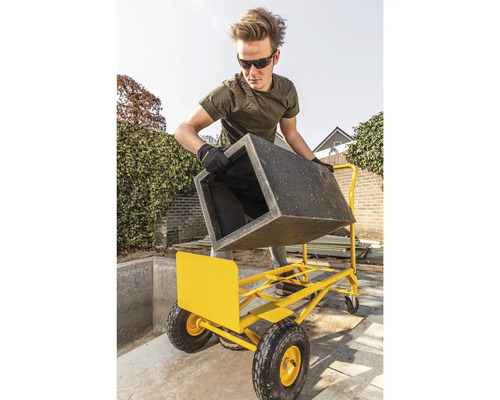 Mann transportiert Pflanzkübel mit Transportwagen im Garten