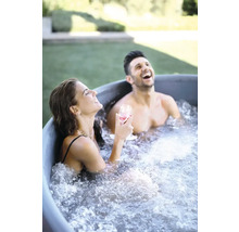 Zwei Personen entspannen lachend in einem Badezuber im Garten