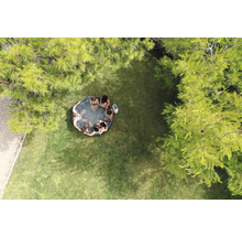 Luftaufnahme eines Gartens mit einem aufblasbaren Whirlpool, in dem mehrere Personen sitzen.