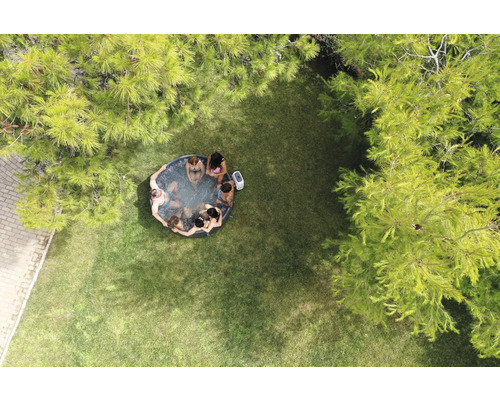 Luftaufnahme eines Gartens mit einem aufblasbaren Whirlpool, in dem mehrere Personen sitzen.