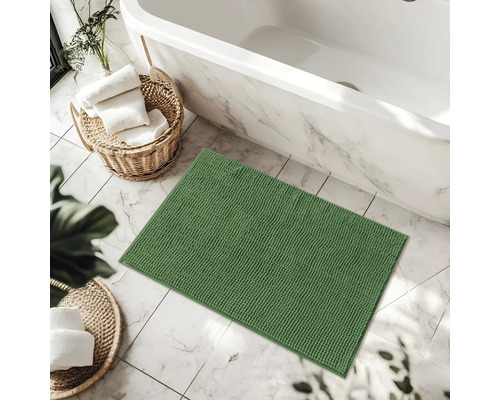 Grüne Badematte im Badezimmer neben Badewanne und Körben mit Handtüchern