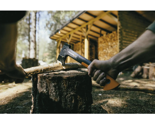 Axt spaltet Holz auf einem Hackklotz im Freien.