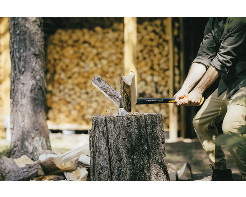 Mann spaltet Holz mit einer Fiskars Spaltaxt auf einem Hackklotz