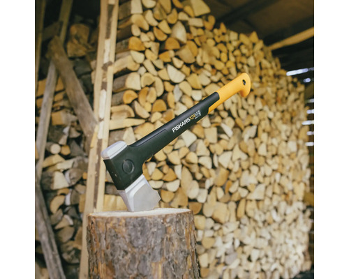 Axt auf einem Holzstumpf vor einem Holzstapel