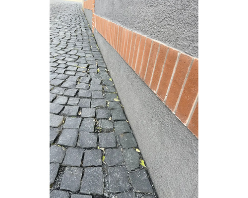 Pflastersteine und eine verputzte Wand mit Ziegelsteinen