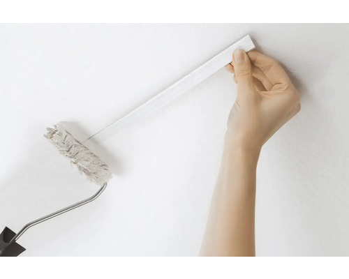 Eine Person verwendet eine Farbrolle mit Teleskopstiel zum Streichen einer Wand.