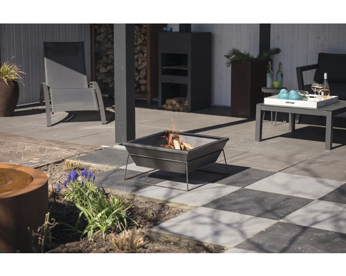 Terrassenszene mit Feuerstelle, Gartenmöbeln und dekorativen Elementen.