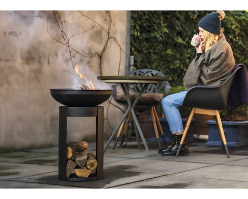 Feuerschale mit Holz und Frau im Garten