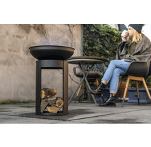 Feuerschale mit Holz und sitzender Person im Freien
