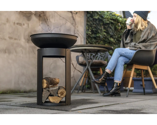 Feuerschale mit Holz und sitzender Person im Freien