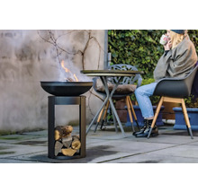 Feuerstelle mit Holz und Person im Hintergrund
