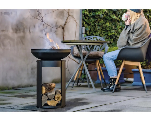 Feuerstelle mit Holz und Person im Hintergrund