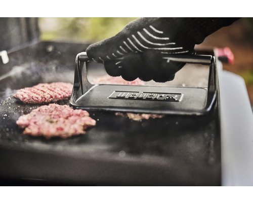 Eine Hand mit Grillhandschuh drückt mit einem Burger-Former Burger auf einen Grill