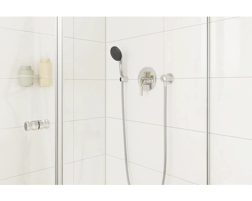 Moderne Duschkabine mit Armatur und Handbrause vor weißem Fliesenhintergrund.