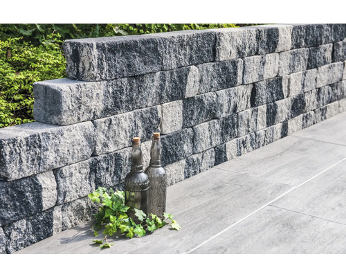 Gestapelte Pflanzsteine bilden eine Gartenmauer.