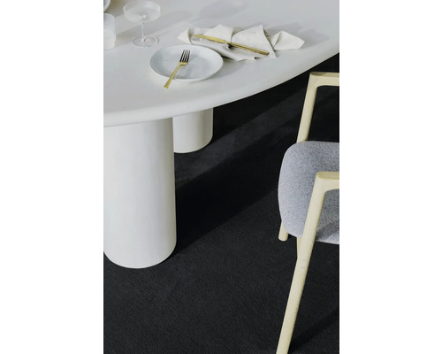 Detailaufnahme eines Zimmers mit einem weißen Tisch, einem Stuhl und einem dunklen Teppich