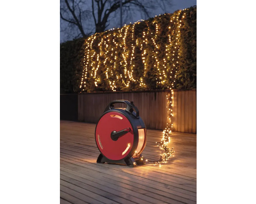 Szene mit einer Lichterkette auf einer Haspel, die einen Strauch im Garten beleuchtet.