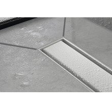 Detailaufnahme einer Duschrinne mit Wasserperlen auf den Fliesen