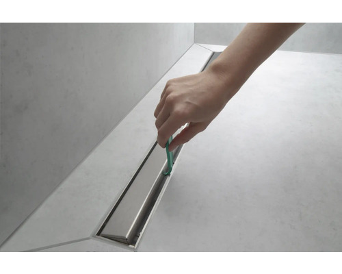 Reinigung einer Duschrinne mit Werkzeug.