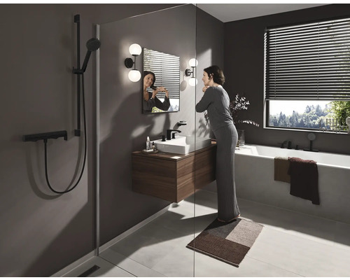 Helles Badezimmer mit Dusche, Waschbecken, Spiegel, Badewanne und einer Frau