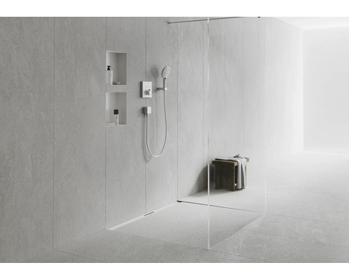 Begehbare Dusche mit Duschkopf, Armatur und Ablagefächern in einer hellen Umgebung.