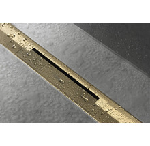 Goldene Duschrinne mit Wasserperlen auf grauen Fliesen