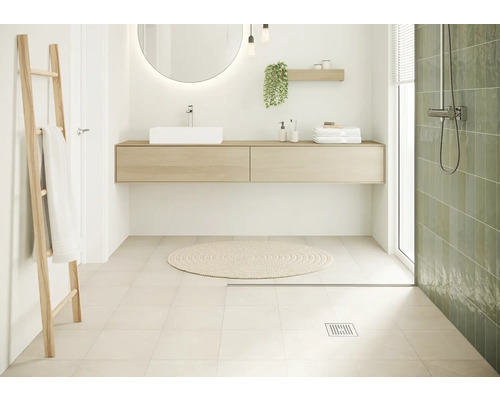 Helles Badezimmer mit Waschtisch, Spiegel, Handtuchleiter und grünen Wandfliesen.