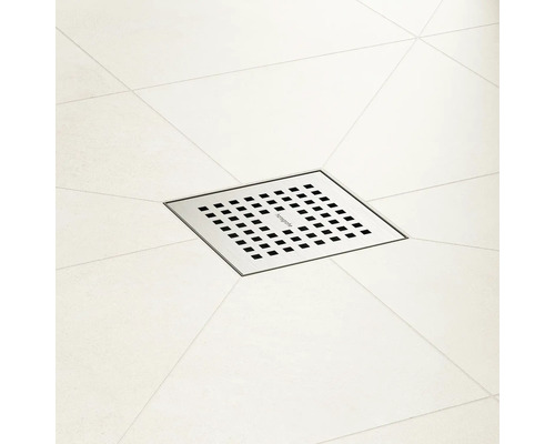 Quadratischer Duschablauf aus Metall mit Löchern auf Fliesen