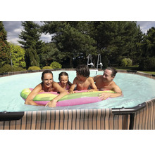 Familie mit Kindern entspannt im Pool mit aufblasbarer Luftmatratze im Garten.