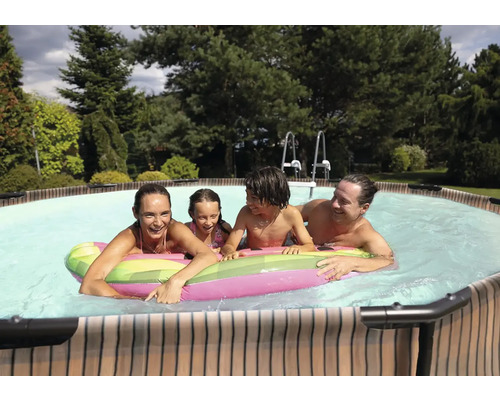 Familie mit Kindern entspannt im Pool mit aufblasbarer Luftmatratze im Garten.