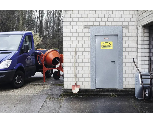 Szene mit Betonmischer, Bauwagen, Schubkarre und Schaufel vor einem Gebäude