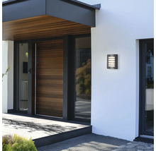 Moderne Hausfassade mit beleuchteter Wandleuchte neben der Haustür.
