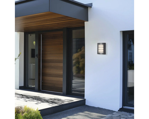 Moderne Hausfassade mit beleuchteter Wandleuchte neben der Haustür.