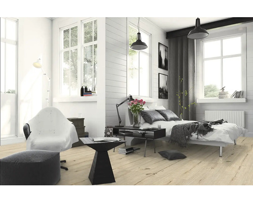 Helles Schlafzimmer mit Bett, Sessel, Stehlampe und Holzboden