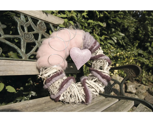 Dekorativer Kranz mit Herzanhänger auf einer Bank