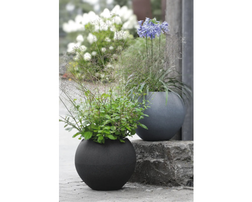 Zwei runde Pflanzgefäße mit Bepflanzung im Garten.