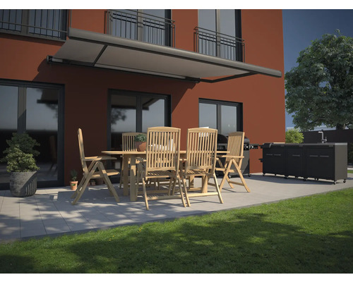 Terrassenszene mit Markise, Gartentisch, Stühlen und Grillküche vor einem Haus