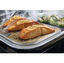 Drei Lachsfilets mit Zitronenscheiben auf einer Grillplatte.