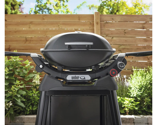 Schwarzer Weber Q Gasgrill mit Standfuß vor einem Holzzaun
