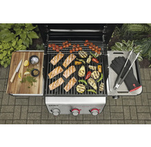 Grillszene mit Lachs, Gemüse und Grillzubehör auf einem Gasgrill